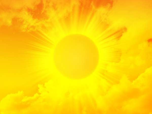 A blazing yellow sun with sun rays against a yellow-red background with clouds; concept is heat-related illness